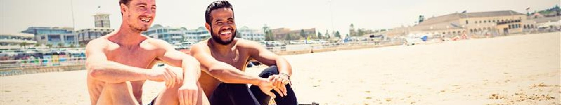 2 guys sitting on a beach taking a short break from one of their stag do activities