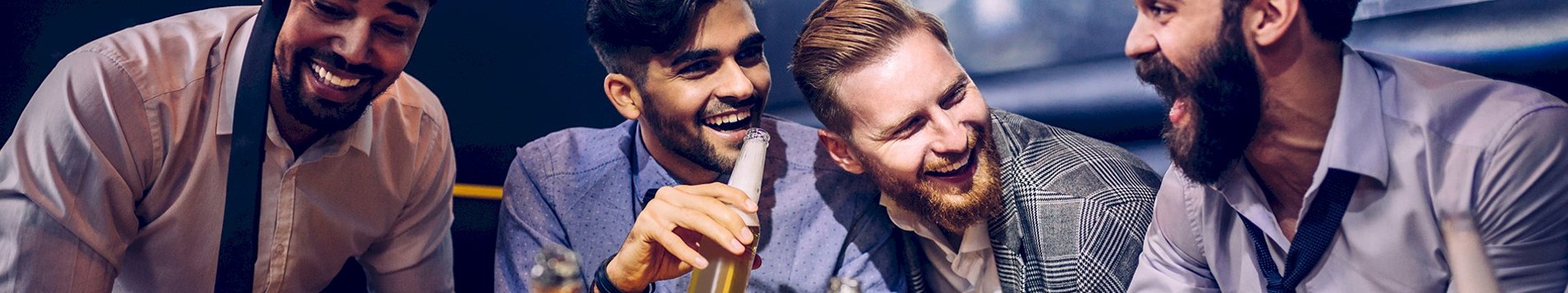 four men laughing and enjoying beers together