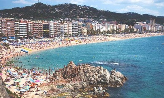 Crowds on the Lloret de Mar beach on a sunny day. Explore Lloret de Mar Stag Party ideas below: